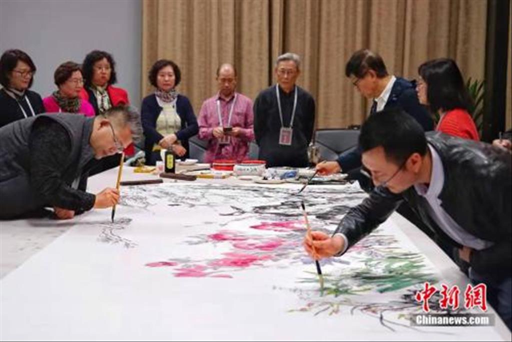 10月22日，重慶美術館舉行了渝臺書畫名家筆會。圖為來自重慶和臺灣的近20名書畫名家，現場揮毫潑墨，共同創作出一幅4米的國畫花鳥作品《團簇》。 羅淋杰 攝