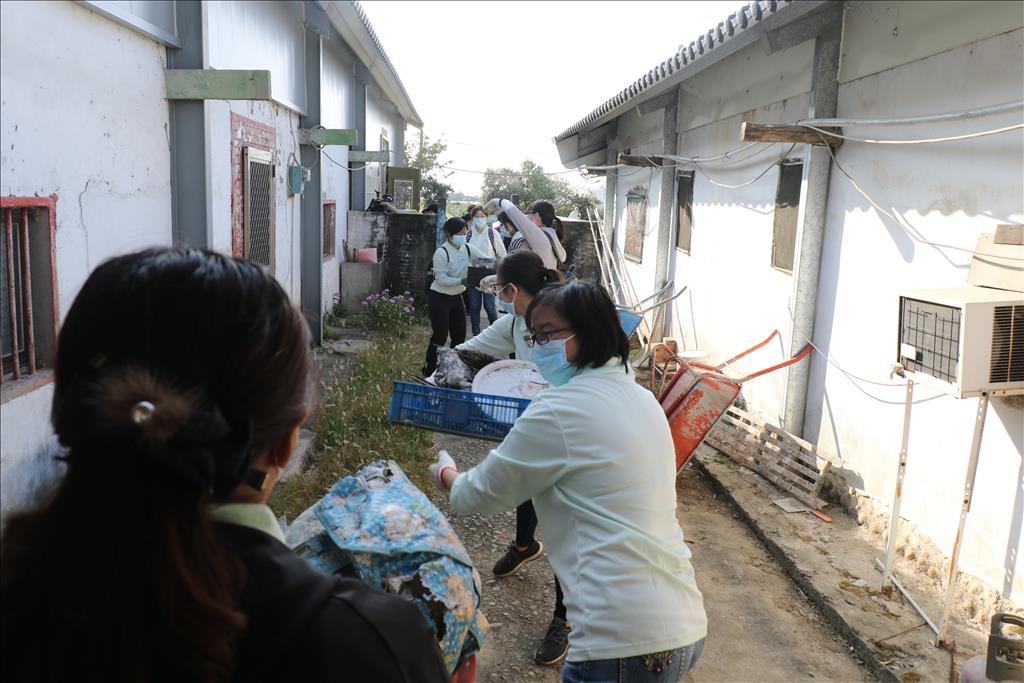 醫護同仁與社區志工以接龍方式將雜物搬出屋外分類。