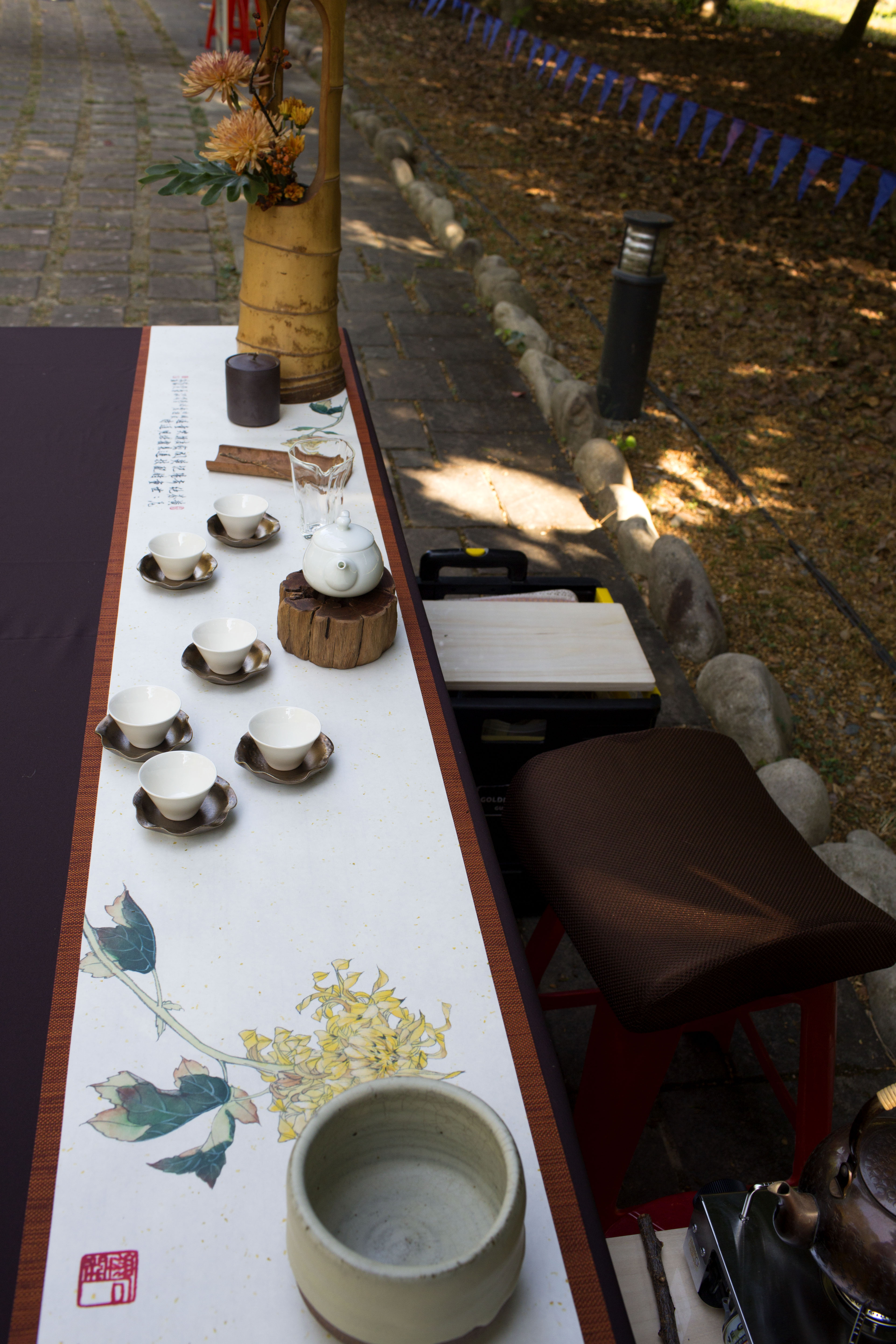 左芳儒老師精心設計此茶席用花藝延伸茶席的視覺，菊與竹的橘紅色調渾成一盞秋意。