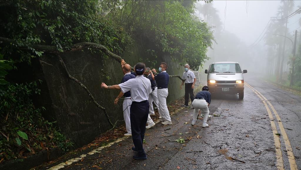志工前往樟湖村往診途中，被從山上滑落的樹擋住去路，志工下車合力移動，繼續往前。（圖為慈濟基金會提供）